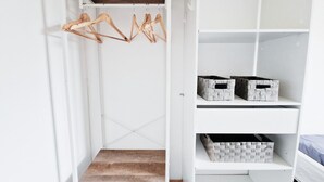 A white closet with wooden hangers, storage boxes, and a wooden shelf.