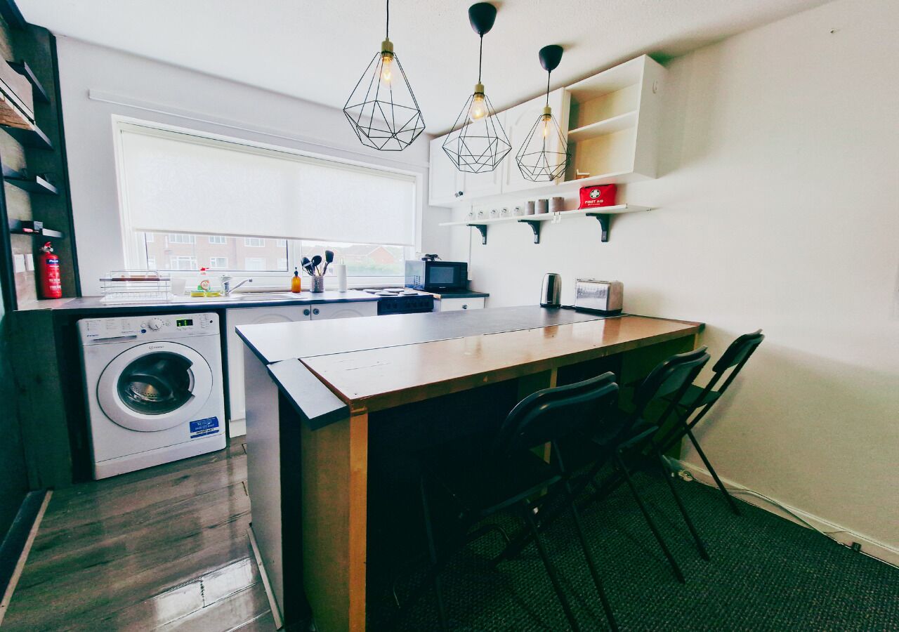 Una cocina compacta con lavadora, una pequeña mesa de comedor y sillas.