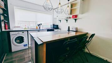 Una cocina compacta con lavadora, una pequeña mesa de comedor y sillas.