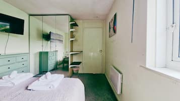 Een hotelkamer met een bed, een spiegel, een televisie, een radiator en een deur naar een badkamer.