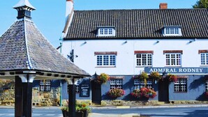 A traditional building with a sign reading "Admiral Rodney" and a stone pavilion in front.