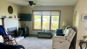 A living room with a fireplace, a sofa, a recliner, a TV, and a large window.