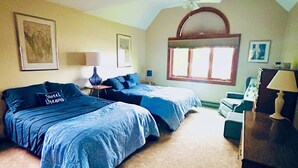 A bedroom with two beds, a window, a desk, and a chair.