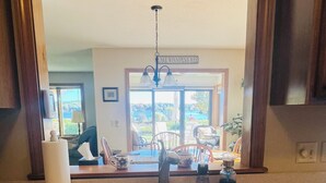 A kitchen with a sink, a mirror, and a view of a dining area with chairs and a table.