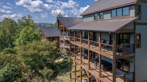 A multi-story wooden cabin with balconies, surrounded by dense forest. - Raccoon Ridge Retreat - Gatlinburg Mountain Escape (Gatlinburg)