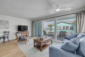 Un salon avec un canapé, une table basse en bois, un téléviseur et un fauteuil.