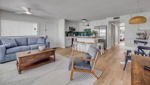 A modern living room with a sofa, a wooden coffee table, and a dining area with a table and chairs.