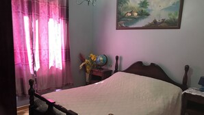 Une chambre à coucher avec un lit en bois, une table de chevet avec une lampe, un globe terrestre et un tableau accroché au mur.