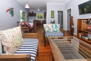 A spacious living room with a wooden dining table, striped sofas, and a glass coffee table.