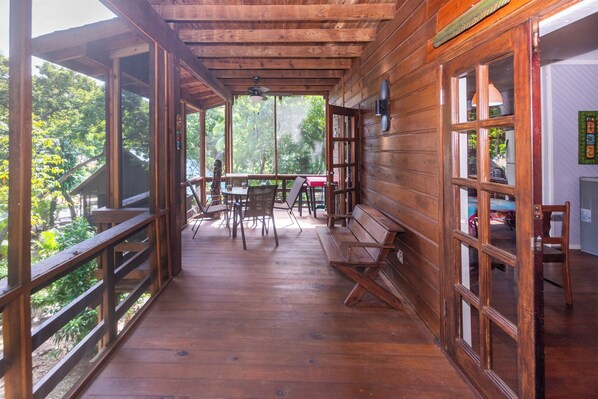 A wooden deck with a table and chairs, a bench, and a view of the outdoors.