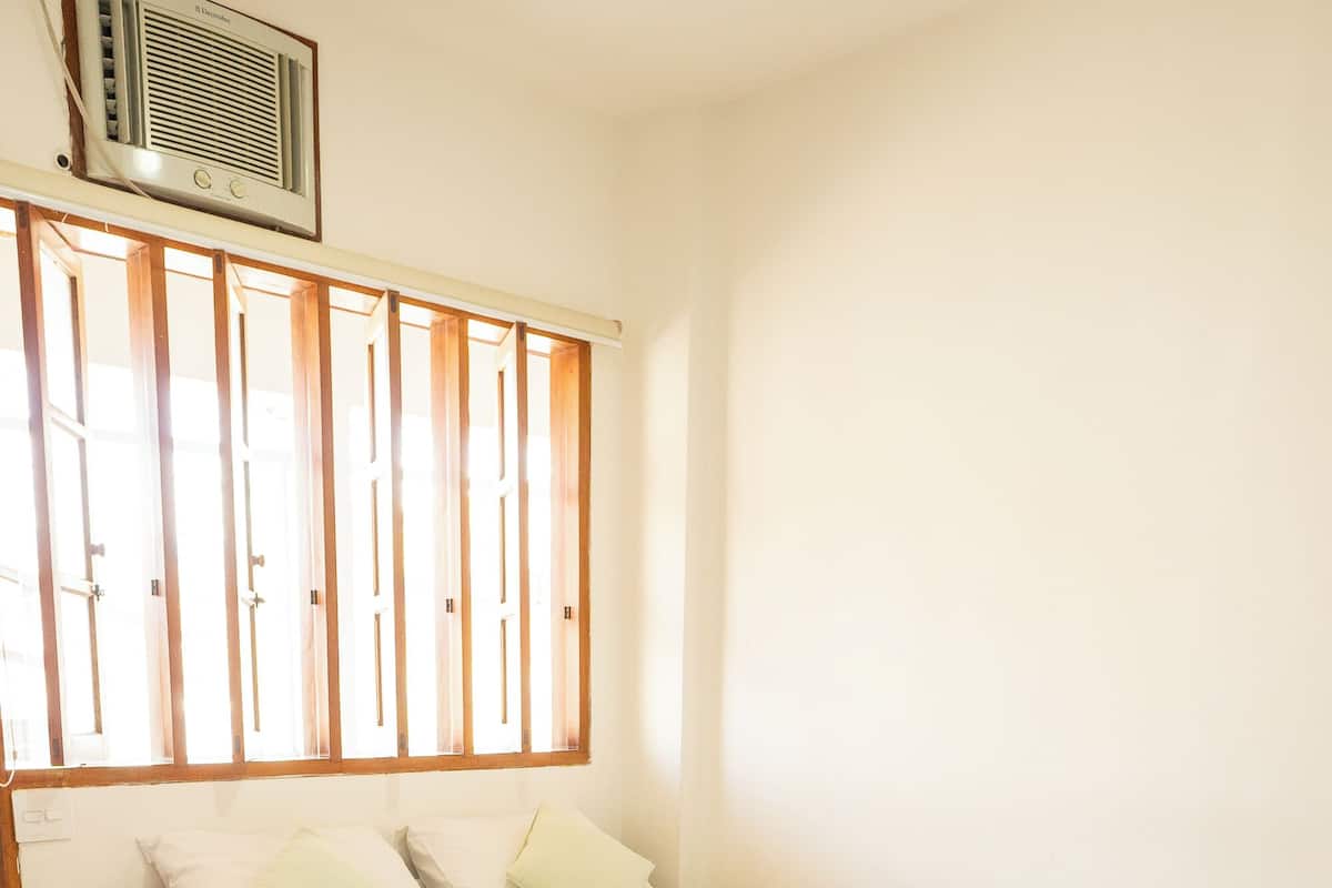 A hotel room with two beds, a window with blinds, and a radiator.