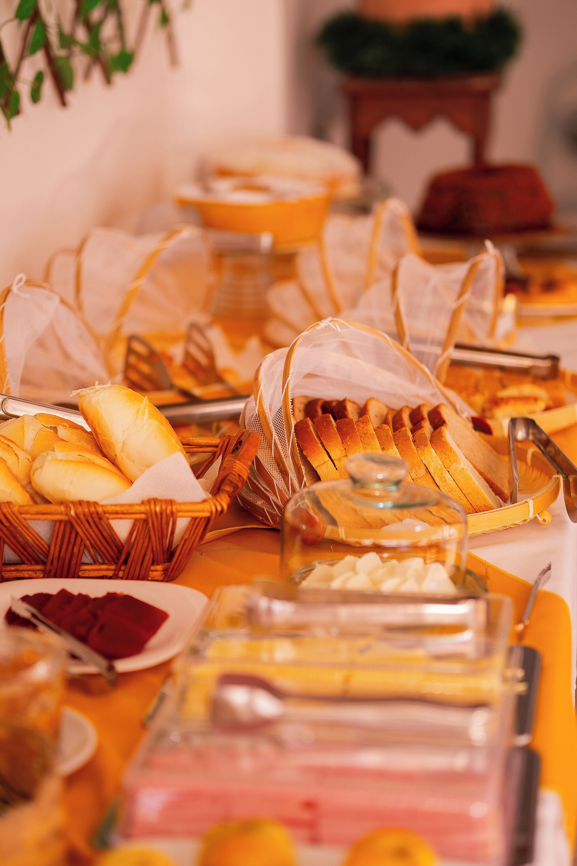 A buffet table with various food items, including bread, pastries, and containers of food.