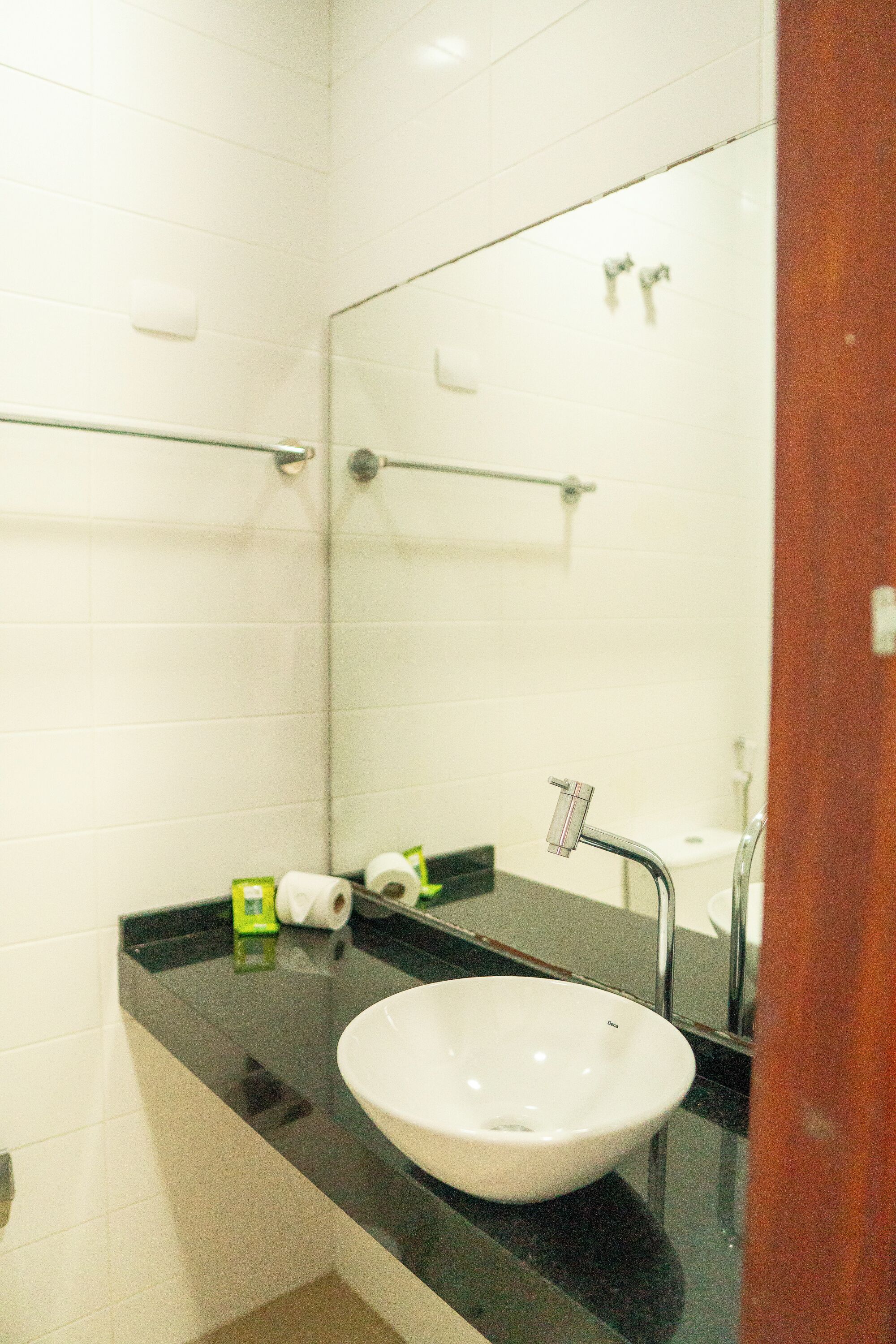 A bathroom with a white sink, a mirror, and a black countertop.