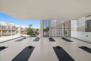 A spacious balcony with black mats arranged for yoga, a view of buildings, and a vertical bamboo screen. - Cozy Getaway w Private Plunge (Tulum Municipality)
