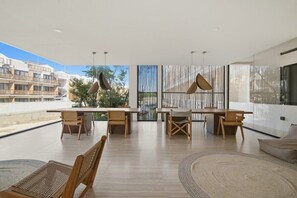 A spacious indoor area with a long table and chairs, large windows, and a view of buildings outside. - Cozy Getaway w Private Plunge (Tulum Municipality)