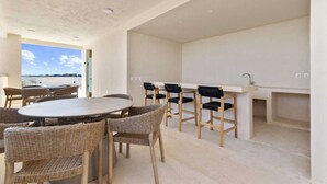 Une cuisine moderne avec un coin repas, comprenant une table ronde et des chaises en osier, et offrant une vue sur la mer.