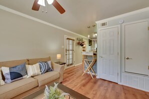 A living room with a beige sofa, a coffee table, and a ceiling fan. - The Homestead Luxury-cozy 2BR Apartments Near SFA (Nacogdoches)