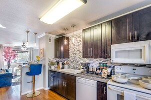 Una cocina moderna con armarios oscuros, un microondas blanco y una estación para café.