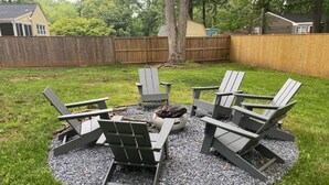 A backyard with a fire pit and four Adirondack chairs arranged in a circle. - Modern Retreat w/ Fire Pit & Parking (Annapolis)