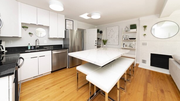A modern kitchen with white cabinets, stainless steel appliances, a central island, and a fireplace. - Modern Retreat w/ Fire Pit & Parking (Annapolis)