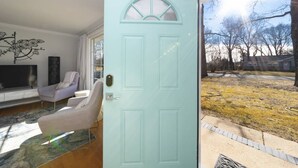 A modern living room with a teal door, a flat-screen TV, and a gray sofa. - Modern Retreat w/ Fire Pit & Parking (Annapolis)