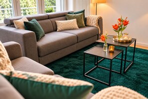 A modern living room with a sectional sofa, a coffee table, and a decorative vase with flowers.