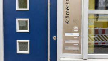 Une porte bleue ornée de trois petites fenêtres et d’une plaque métallique portant l’inscription « Kramerstrasse 6 ».