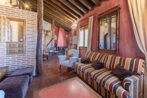 A cozy room with a striped sofa, a wooden chair, and a brick wall.