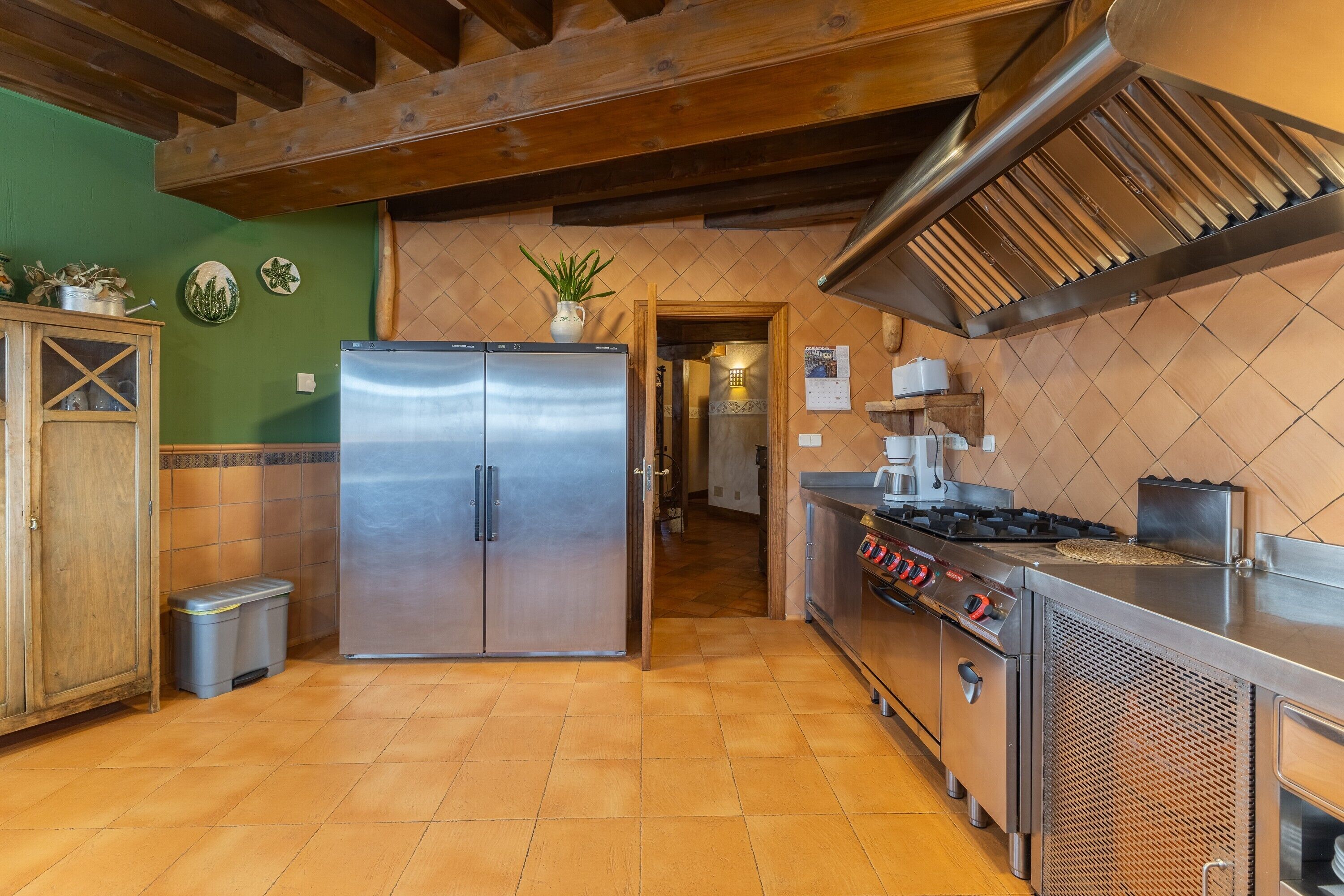 Una cocina con un refrigerador de acero inoxidable, una estufa y vigas de madera en el techo.