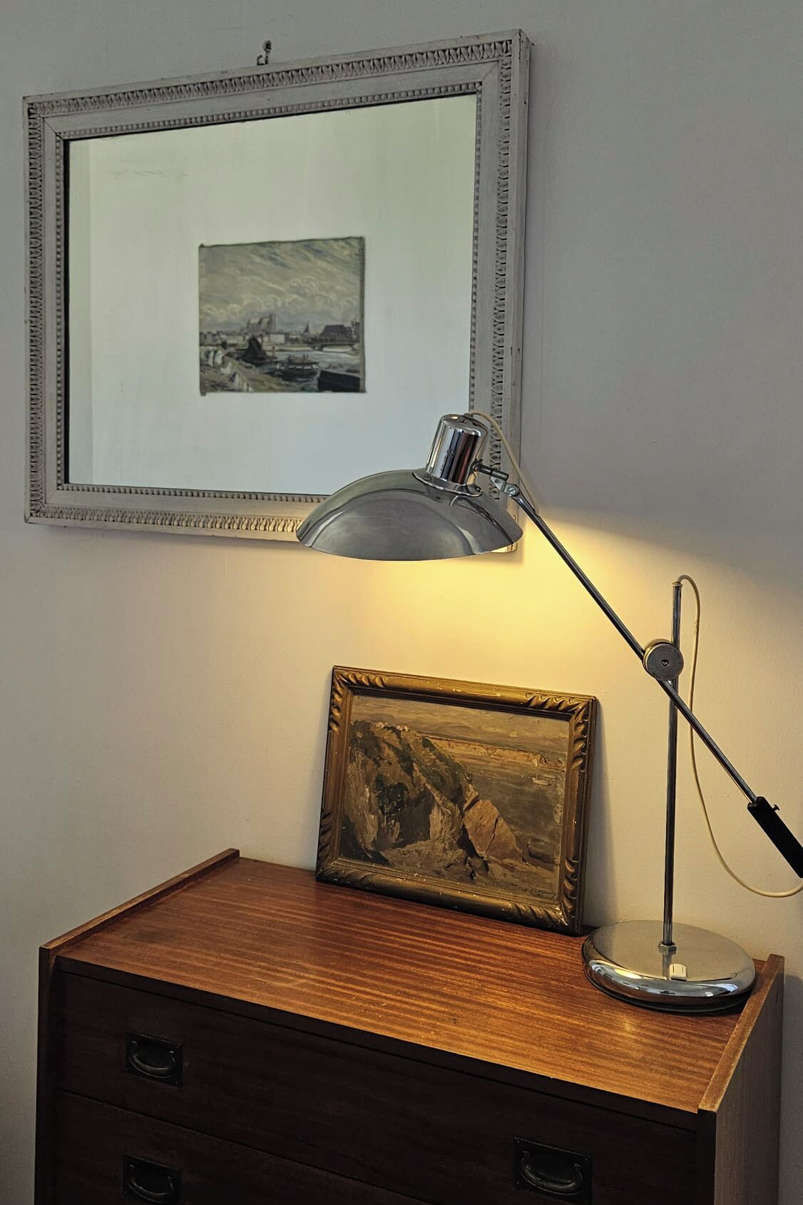 A desk with a framed painting and a desk lamp.