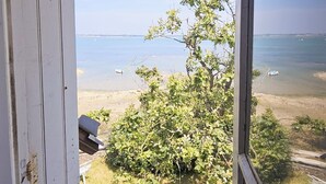 Een kamer met uitzicht op een strand, een raam en een deur.