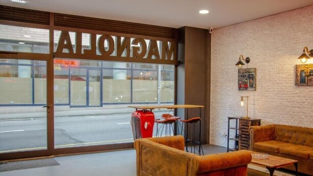 A modern interior with a large window, a red heater, and two sofas. - Magnolia Suites & Stays :Standard Suite (Porto)