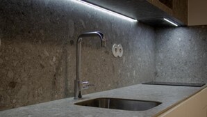 A kitchen with a modern faucet, a double sink, and a backsplash. - Magnolia Suites & Stays :Standard Suite (Porto)