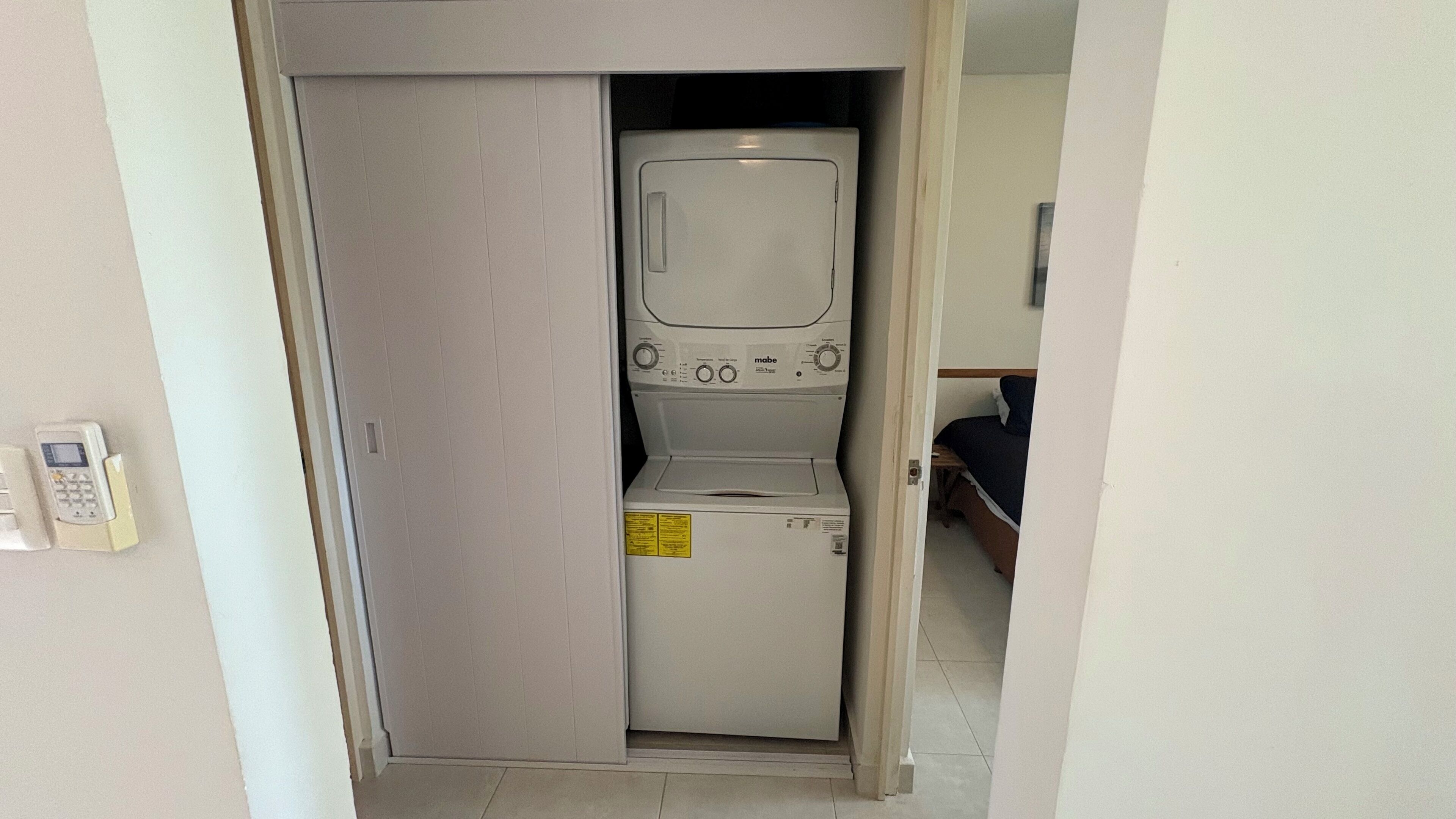 A compact laundry room with a washing machine and dryer, a small step stool, and a telephone.