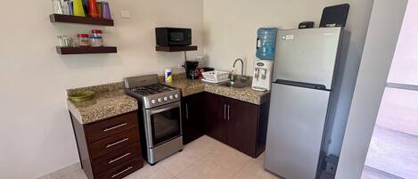 A compact kitchen with a gas stove, oven, microwave, and a refrigerator.