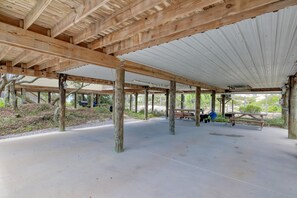 An open pavilion with a wooden roof and concrete floor, supported by wooden posts. - Whitesands Beach House - North (Gulf Shores)