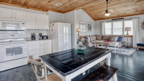 A modern kitchen with white cabinets, a black countertop, and a wooden ceiling. - Whitesands Beach House - North (Gulf Shores)