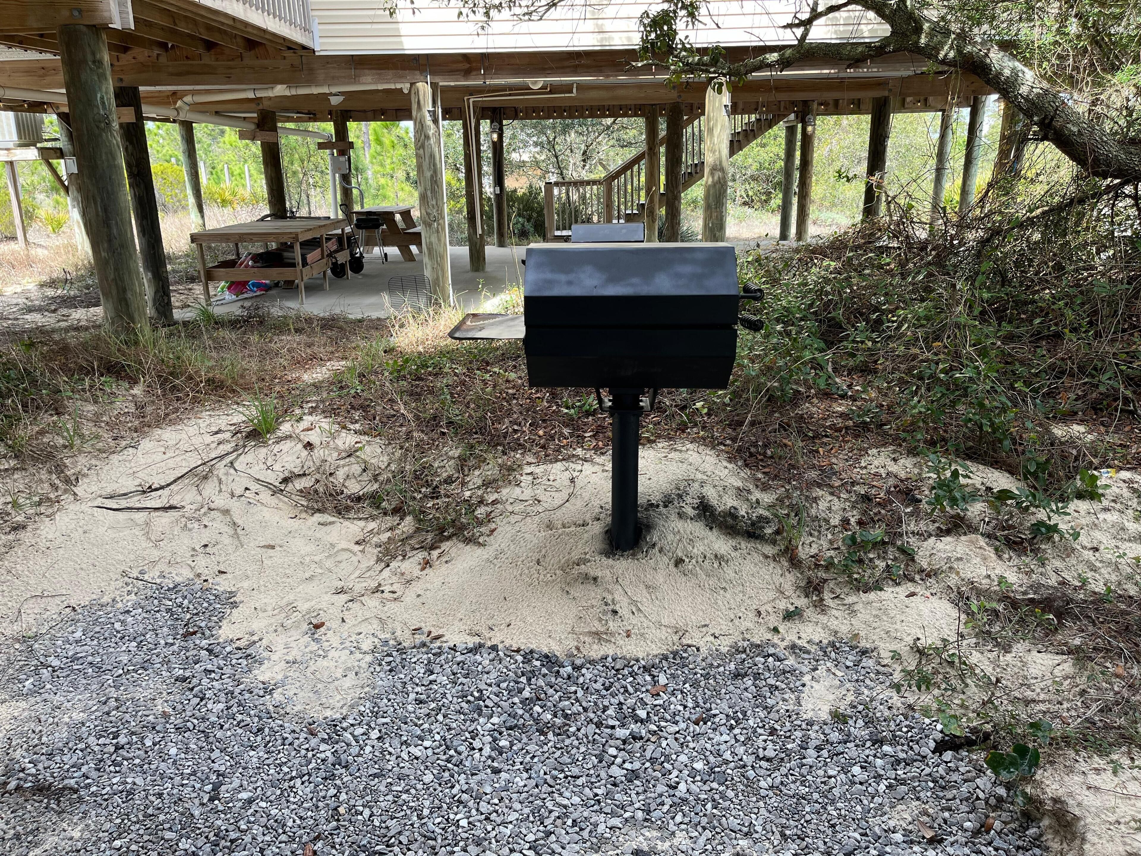 A covered outdoor area with a barbecue grill, picnic tables, and a wooden deck.