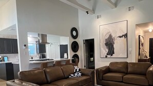 Ein großzügiges Wohnzimmer mit zwei braunen Ledersofas, einem gemusterten Teppich und einem Deckenventilator.