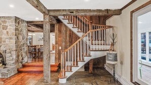 A wooden staircase with stone walls and a stone fireplace.