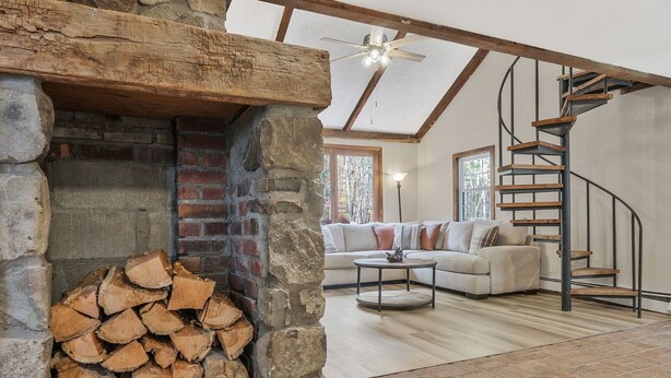 A cozy living room with a stone fireplace, a wooden staircase, and a comfortable sofa. - Unique Perfect for Families/Groups+Indoor Pool (Wurtsboro)