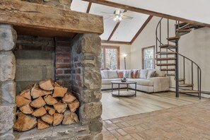 A cozy living room with a stone fireplace, a wooden staircase, and a comfortable sofa.