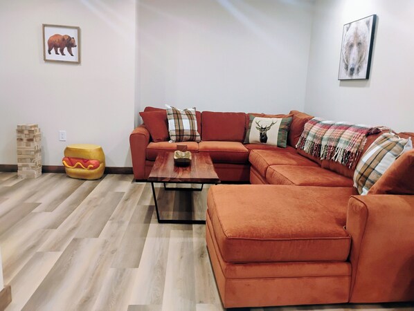 A living room with a sectional sofa, a coffee table, and a wooden floor.
