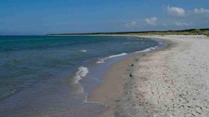 Una playa con agua azul cristalina y una orilla arenosa.