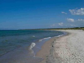 Una playa con cielos despejados y aguas tranquilas.