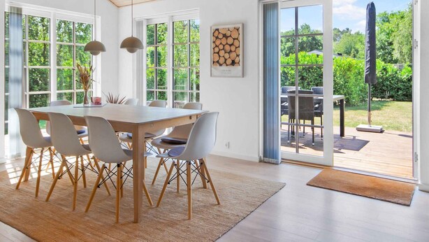 Un comedor con mesa y sillas de madera, ventanas amplias y vistas al exterior.
