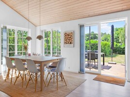 Un comedor con mesa y sillas de madera, ventanas amplias y vistas al exterior.