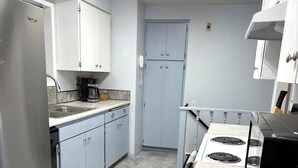 Une cuisine de taille réduite, équipée d’un réfrigérateur, d’une cuisinière et de placards.