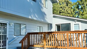 Une maison à deux étages dotée d’une terrasse en bois et d’un patio couvert.