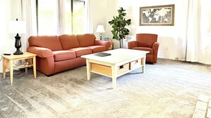 Un salon comprenant un canapé, un fauteuil, une table basse, une lampe et une plante.